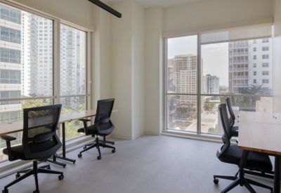 Bright office space featuring four workstations facing large windows with urban views.