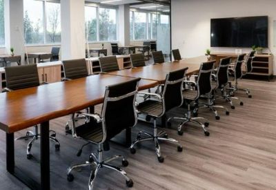 Large conference room with a long wooden table, black ergonomic chairs, and large windows.