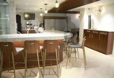Modern lounge area with wooden bar stools, marble countertops, and warm overhead lighting.