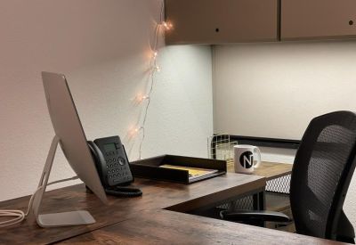 Private office workstation featuring a wooden desk, black mesh chair, and decorative string lights.