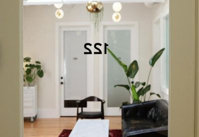 Reception area seen through an office door with globe pendant lighting and a leather sofa.