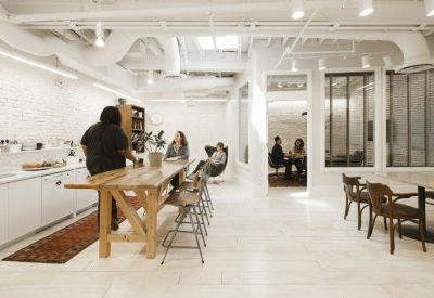 Bright communal kitchen area with a large wooden island table and seating.