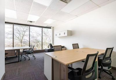 Bright shared office space with multiple desks and large windows.