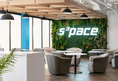 Lounge area featuring a lush green moss wall with glowing company signage.