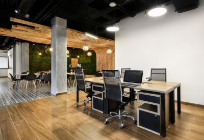 Bright open-plan office area with wooden desks, ergonomic chairs, and polished flooring.