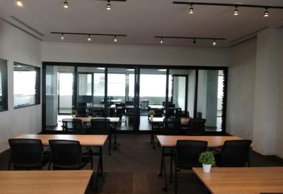 Professional meeting room featuring multiple tables and chairs under track lighting.