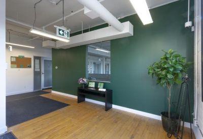Spacious reception area with a green feature wall, wooden flooring, and potted plant.