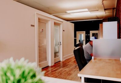 Modern office hallway with hardwood floors, white doors, and a frosted glass partition.