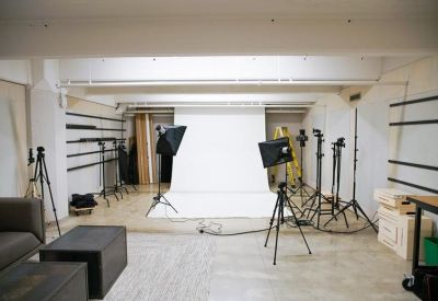 Professional photography studio space with a white backdrop and lighting equipment.