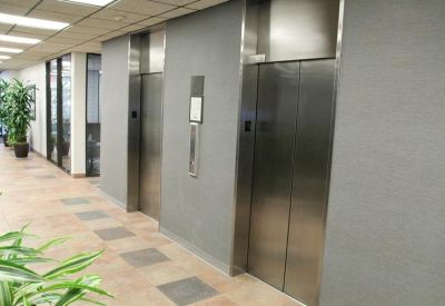 Polished elevator bank with framed artwork and decorative plants.
