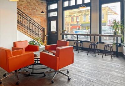 Breakout space with orange armchairs and a window bar overlooking the street.