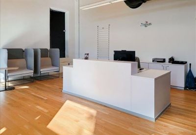 Clean, white reception desk in a lobby with warm hardwood flooring.