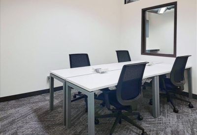 Private four-person office suite with white desks and black mesh chairs.