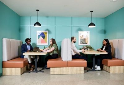 Team members collaborating in modern leather booth seating with teal accent walls.