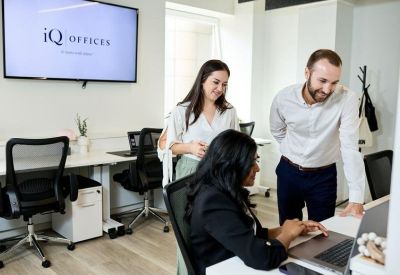 Bright, modern office suite featuring white desks, black ergonomic chairs, and brand logo.