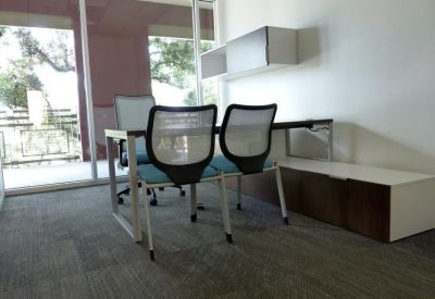 Private office with a white and wood desk and a window looking out to trees.