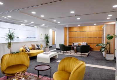 Spacious coworking lounge with yellow shell chairs and velvet sofas.