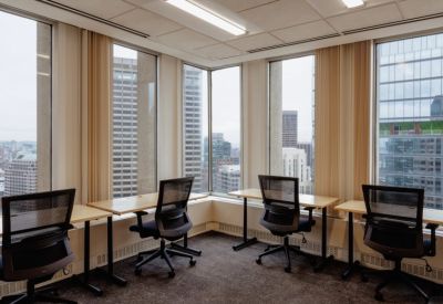 Coworking area featuring four individual desks by large windows with city views.