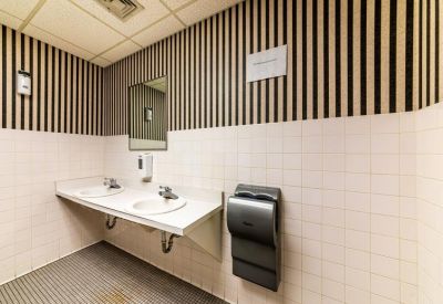 Restroom featuring two white sinks and striped wallpaper.