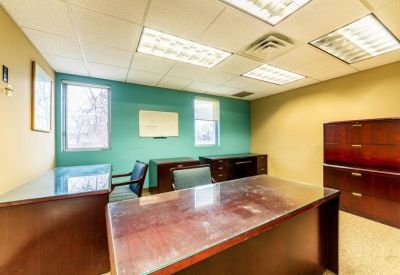 Internal office with wood furniture and large windows.