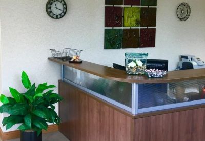 Reception desk with wood paneling, glass accents, and a large colorful wall art piece.