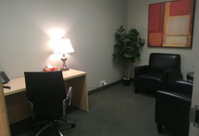Private office featuring a wooden desk, lamp, and black leather armchairs.