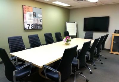 Large meeting room with a light wood conference table and black leather chairs.