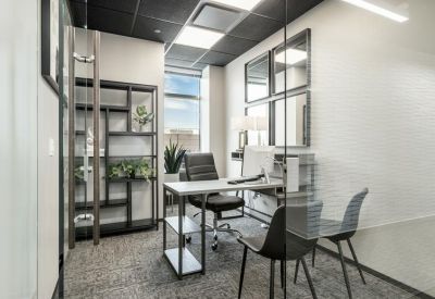 Private office suite with a modern desk, shelving unit, and guest seating.