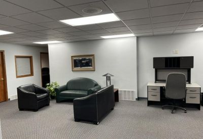 Spacious open office area with a sofa, armchairs, and a built-in workstation.