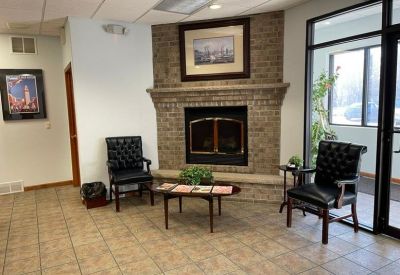 Lobby area featuring a brick fireplace, leather chairs, and tile flooring.
