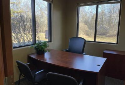 Private office suite with a wood desk, leather chair, and window views.