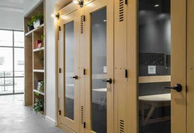Row of private yellow phone booths with glass doors and individual wall sconces.