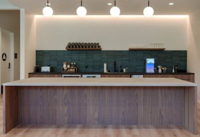 Modern communal kitchen with dark blue tiles, wooden cabinets, and a large island.