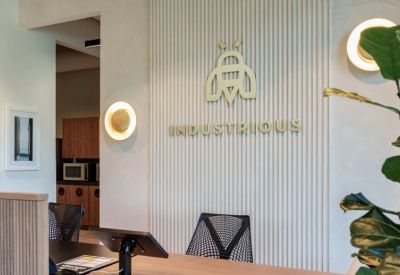Branded reception area with textured walls, warm lighting, and the Industrious logo.