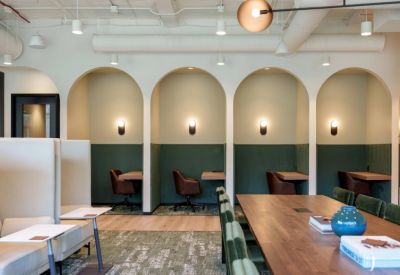 Arched individual coworking nooks with green walls and leather chairs.