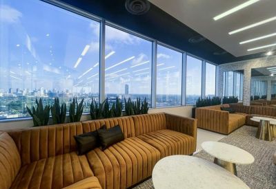 Lounge area with plush velvet seating, snake plants, and floor-to-ceiling windows overlooking the city.