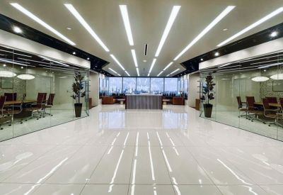 Spacious white marble reception area with linear ceiling lights and glass-walled meeting rooms.