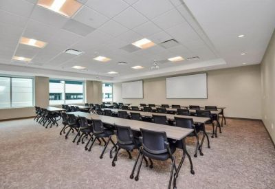 Spacious training room with multiple rows of tables, black chairs, and dual whiteboards.