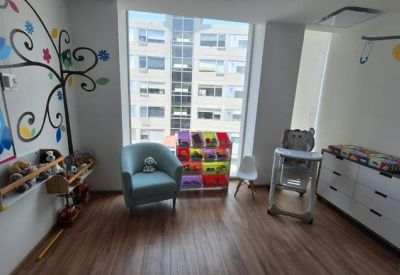 Colorful playroom with an owl mural, blue armchair, and views of 2430 Carretera México-Toluca.