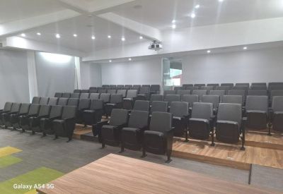Modern lecture hall with rows of black tiered seating and recessed lighting.