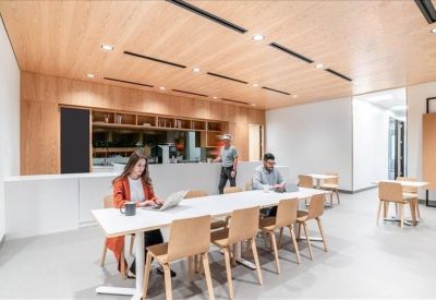 Bright dining area with long white communal tables and wood-paneled ceiling.