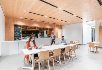 Coworking space with long white tables and ergonomic wooden chairs.