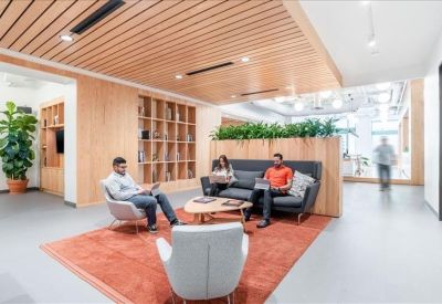 Informal lounge with grey armchairs, a rug, and large wood-framed bookshelf.