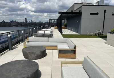 Furnished rooftop terrace with grey sectional sofas and stone coffee tables overlooking the city.
