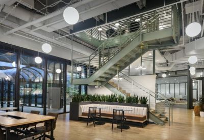 Open-plan coworking hub with a grand metal staircase and integrated planter boxes.
