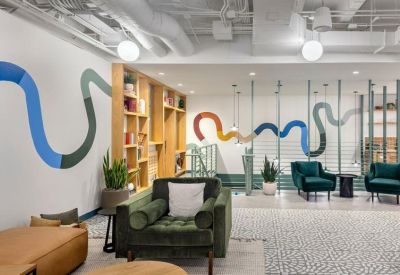 Bright breakout space featuring a colorful wall mural and plush green armchairs.