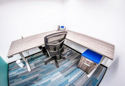 Individual L-shaped desk workstation with an ergonomic chair and blue accents.