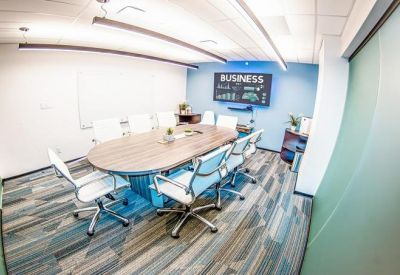 Professional boardroom with a large wooden table, white chairs, and a glass wall.