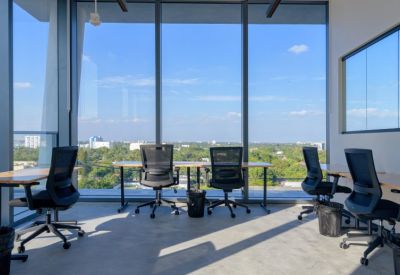 Modern workspace with black ergonomic chairs and wooden desks facing floor-to-ceiling windows.