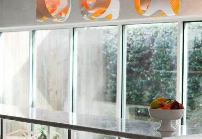 Modern light fixtures hanging over a sleek breakfast bar with high stools.